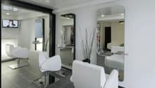 Spacious hair salon with modern, minimalist decor. White chairs and tables, black and gray tile flooring, large mirrors, and decorative branches. Appears to have a dishwasher visible in the background.