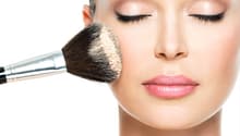Close-up of a woman applying powder makeup with a brush