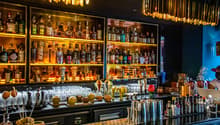 bar counter with multiple shelves filled with alcohol, various glasses and bottles, a hot air balloon, fruits, lamps, and decorations