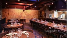 A restaurant with wooden tables and chairs, a long counter, and a hexagonal wall design.
