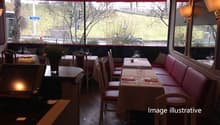 A restaurant with tables and chairs, a counter, a monitor, a lamp, and a red awning.