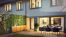 2 story house, gray walls, wooden doors, large windows, dining table with chairs in terrace, potted plants