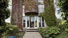 Modern house covered in ivy, wooden pathway, three stories, glass doors and windows