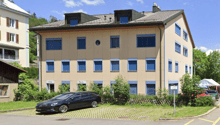 3 story building, beige exterior, blue shutters, car parked in front