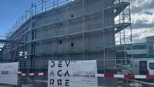 Under construction building, metal scaffolding, large banner with text
