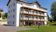 3 story building, balcony, multiple windows, parking area, green lawn