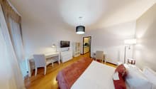 room contains a desk with chair, bed, lamp, TV and shelves