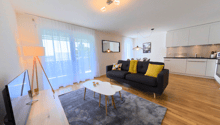 large windows, black sofa, white table, beige carpet, floor lamp, flat screen tv
