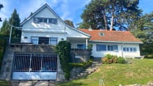 Two story house, white exterior, red tile roof, metal garage doors, large balcony, steps leading up to the front entrance