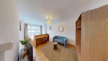 study room with desk and chair, couch, round table, carpet, lamp, television, potted plant, mirror, picture frame, window with curtains