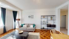open living room, grey couch, table, wooden floor, lamps, shelves