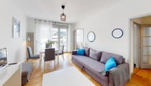 living room with dining area, gray couch, white table, chairs, white rug, white walls, wooden floor, white curtains, lamps, mirror, picture frame, television
