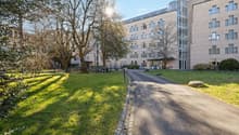 Large modern building with multiple windows and two glass doors. Green grass lawn. A wide driveway.