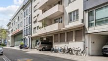 A multi-story building with balconies, a garage, and bicycles parked in front.
