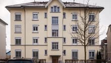 4 story building, beige walls, white windows, brown door, car parked in front