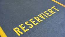 The image shows a parking lot with a large 'RESERVED' text painted in yellow on the asphalt surface.
