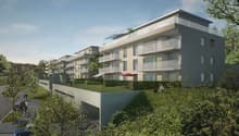 Multistory apartment building, with multiple balconies and windows, greenery, driveway and parking