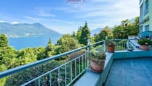 Balcony with a view of the lake and mountains, potted plants, tiled floor, railing