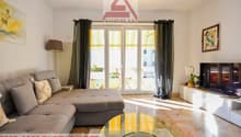 gray sofa, coffee table, floor lamp, artwork, sliding glass door to balcony, white tv stand, television, small potted plant