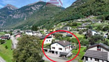 House in mountain village, white exterior, large windows, driveway, surrounding trees and plants