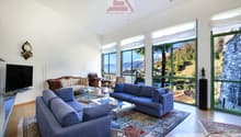 large windows, blue couches, glass coffee table, TV stand, clock, statue, carpet, large windows with mountain views