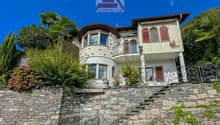 Two-story house, stone wall, balcony, arch windows, statue on top of the wall