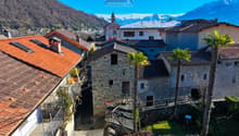 Stone buildings, red roofs, balconies, mountains in the background