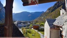 Aerial view of a village with a building, surrounded by mountains and a green field