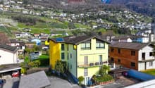 Large multi-story building, yellow paint, balcony, mountain view