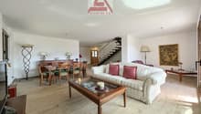 living room with wooden floor, white couch, wooden coffee table, dining table, wooden chairs, wooden cabinet, lamps, painting, TV