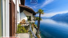 House with balcony, overlooking the lake, mountains in the background, palm trees
