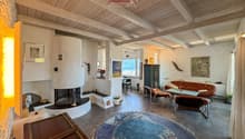 wooden ceiling, fireplace, large windows, couch, armchairs, rug, side table, artwork