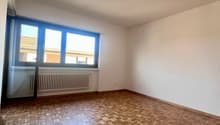 Empty room with wooden parquet floor, white walls, large window, white radiator, sliding glass door