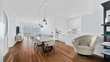 modern interior, hardwood floor, large windows, dining table with chairs, white walls, white cabinets, built-in television, floral vase, modern chandeliers, contemporary armchair, black shelf