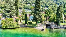 Lakefront villa, multiple buildings, lush greenery, mountain backdrop, swimming pool