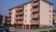 Apartment building with balconies, garages, and parking in front