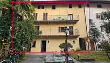 Three story house, yellow, two balconies with chairs, streetlight, entry door, bike rack