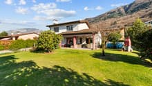 2 story house, white exterior, brown roof, large lawn, trees, mountains in the background