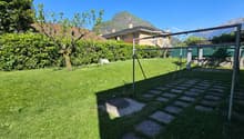 Green lawn, hedges, trees, playground equipment, mountains in the background