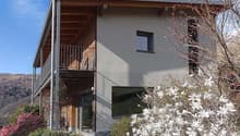 modern house, 2 stories, balcony, large windows, gray exterior, wooden accents, surrounded by greenery