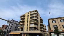 Multi-story building with balconies, storefronts, and a parking sign