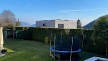 A garden with a trampoline, hedges, and a view of the mountains