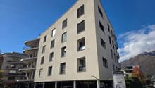 Contemporary apartment building, multiple floors, modern design, several windows, underground parking area, and signage indicating residence.
