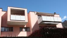 2 storey apartment building with pink exterior, two balconies