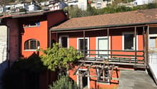 Terraced house, red brick walls, wooden balcony, windows with white frames, solar panels on the roof