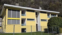 3 story yellow house, white trim, multiple windows, fenced yard, mountain in background