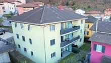 A yellow apartment building with multiple balconies and a tiled roof