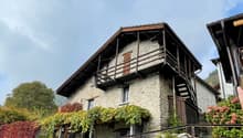 stone wall, wooden balcony, wooden door, wooden staircase, plants on the wall, red leaves, mountain in the background