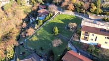 Aerial view of a residential area with several houses, a large grassy field, and a road.