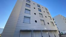 modern apartment building, multiple windows, garage below, bright exterior, four floors